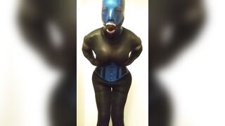 trans doll grabbing her breasts and booty in latex mask.