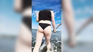 Fat sissy walks along public beach and plays in the water