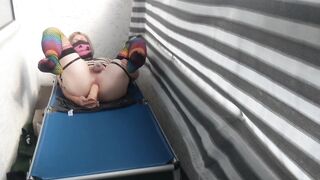 Caged sissy plays with her sex toy on public balcony