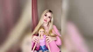 Fascinating blond girl in pink teasing with her doll